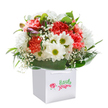 From the heart of Harold Hill, this bouquet reflects the spirit of the area's lively community and green landscapes. Shining in a crisp white gift bag, the flowers are arranged to showcase lush, frilly carnations in shades of sunset coral, peach, and deep red. Dancing among them, fresh white daisies announce themselves with shining yellow-green eyes, while the whimsical touch of baby's breath gives the whole piece a dreamy, airy finish-like wildflowers found along the paths of local parks. Hints of purple-tinged buds peak out shyly on one side, offering the quiet promise of flowers yet to bloom. A bounty of glossy dark green leaves surrounds the arrangement, the texture rich and the colour deep, much like Harold Hill's tree-lined streets after a rain shower. The arrangement sits upright in a square white bag with elegant ribbon handles, ready for easy gifting and delivery across Harold Hill-a thoughtful gesture for any occasion, from birthdays to new beginnings. Captured in clean, soft light against a white backdrop, the bouquet radiates freshness and a sincere sense of celebration, expertly brought together by hands that know the character and kindness found in every corner of Harold Hill.